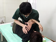 横向きに寝る患者さんの肩を包み込むような手技施術
